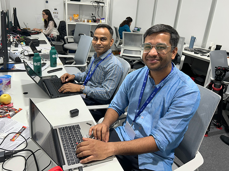Reporters Gaurav Saini and Sibi Arasu work in the AP office at COP28. (Photo by Devon Terrill)